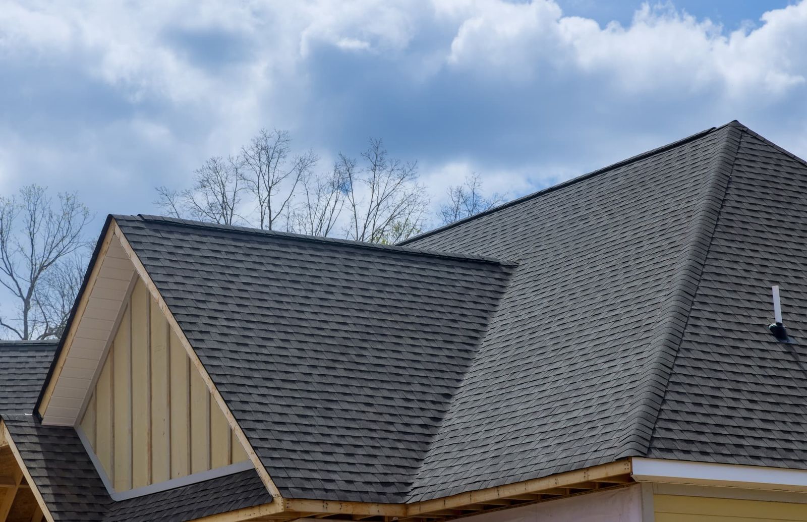 Dark grey asphalt shingles across the intersecting gable slopes of a new roof.